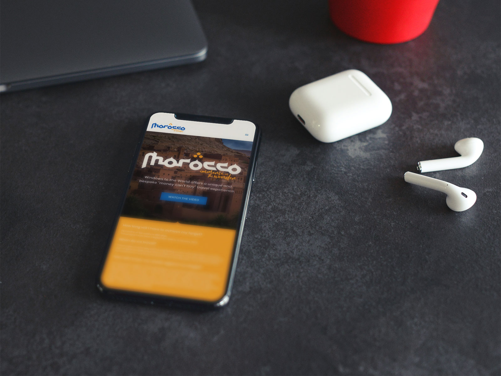 Morocco website on a smartphone lying on a bench next to airpods